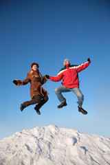 Fototapeta na wymiar couple jump on top of snow hill