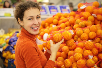 young  woman with oranges in store