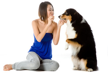 A woman has a treat for her dog on white background
