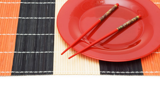 Red plate with chopsticks isolated on white