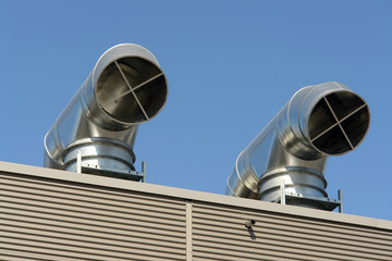Two roof air condition outlets over blue sky