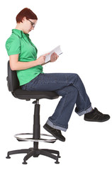 Fototapeta na wymiar Redheaded girl sitting on a high chair and reading a book.
