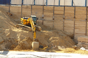 Digger working on sand heap at excavation site