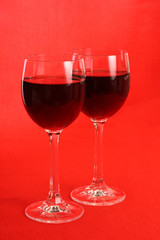 Two glasses of red wine on red background