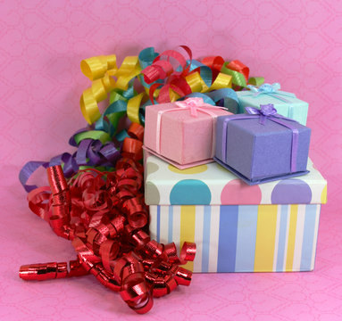 Piile of Gifts on Pink background with Colorful Curly Ribbons