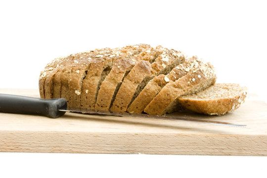 Slice brown soad bread on wooden board with knife