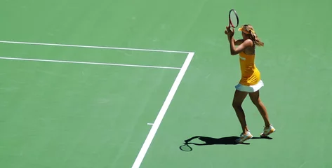Deurstickers a girl in tennis action.  Yellow dress and green tennis field © kris@Positief