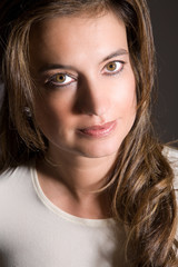 Naklejka premium Beautiful brunette in closeup portrait on dark background