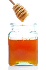Pouring honey on glass jar, on white background