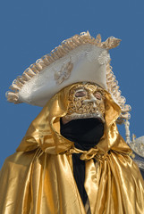 Carnival Venetian disguise with golden mantle on blue sky