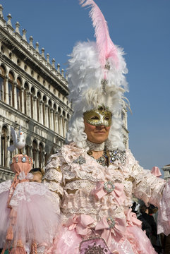 Woman wearing a pink Venetian disguise with hat of plumes