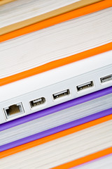 Vertical image of close-up of white laptop between books