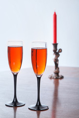 An image of two wineglass and red candle