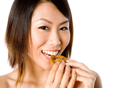 A Pretty Asian Woman Eating A Cookie