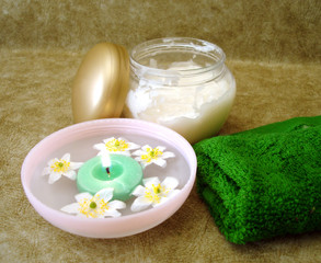 Obraz na płótnie Canvas cosmetic moisturizing cream and candle with flowers