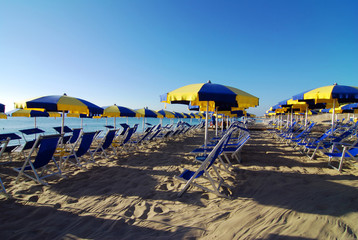 Empty beach with umbrellas and sea shortly after the sunrise