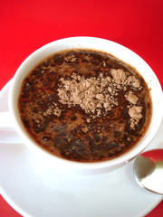 white cup of coffee with spoon on red background