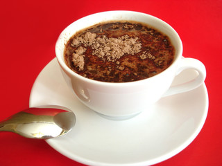 white cup of coffee with spoon on red background