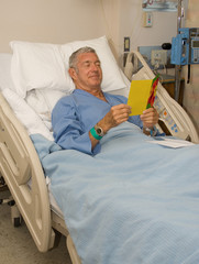 Man in hospital bed reading a get well card