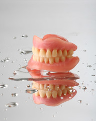 artificial teeth on reflecting background, with water drops