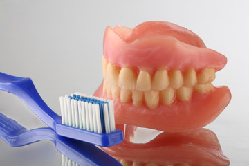 artificial teeth on reflecting background with teeth brush