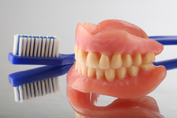 artificial teeth on reflecting background with teeth brush