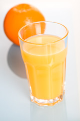Fototapeta na wymiar A glass of cold and refreshing orange juice and an orange