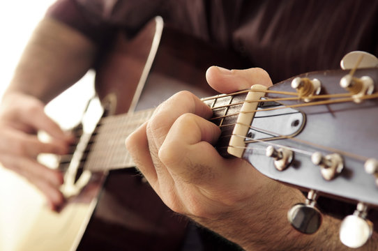 Hands of a person playing an acoustic guitar close up