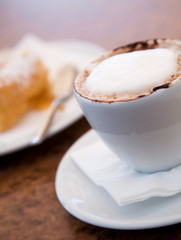 Cappuccino and delicious pastry on cafe table