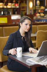 pretty woman  in a cafe with a cup of tea working on laptop