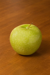 a single green apple on a wooden table