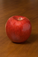 a single red apple on a wooden table
