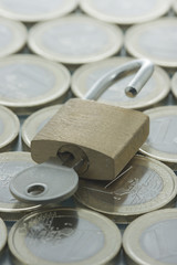 Euro coins pattern and opened padlock with key