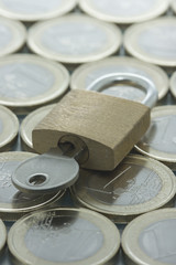 Euro coins pattern and closed padlock with key