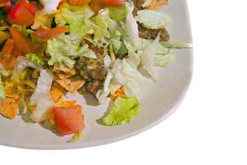 A plate of taco salad with tomatoes, lettus and cheese