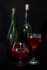 Red wine bottles and glass isolated over black