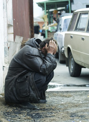 Sad homeless man in despair on city street