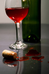 Spilled Red wine and cork with bottle and a glass 