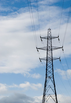 Electricity pylon against deep blue sky with white clouds