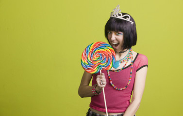 Pretty young woman takes a bite from a large lollipop © Scott Griessel