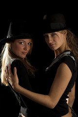 two girls in black hats on black background