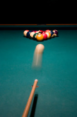 Shooting the white ball to break the racked billiard balls..