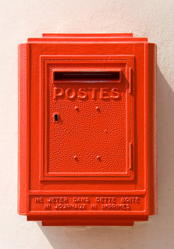 Red French mail box on a wall.