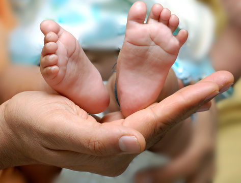 close up of a father's hand cradling babies feet