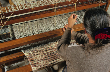 FEMME TRAVAILLANT SUR UN METIER A TISSER