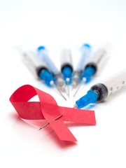 syringe and aids ribbon sign isolated over white. shallow dof