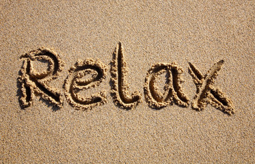Relax, written on a sandy beach.
