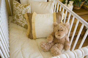Baby bedroom with crib, pillows and a teddy bear.