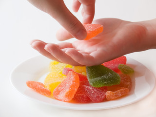 Woman's hands taking the sweet marmalade pieces from the plate