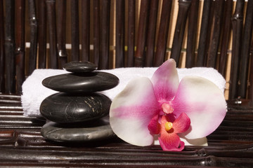 Massage stones and orchid flowers on bamboo